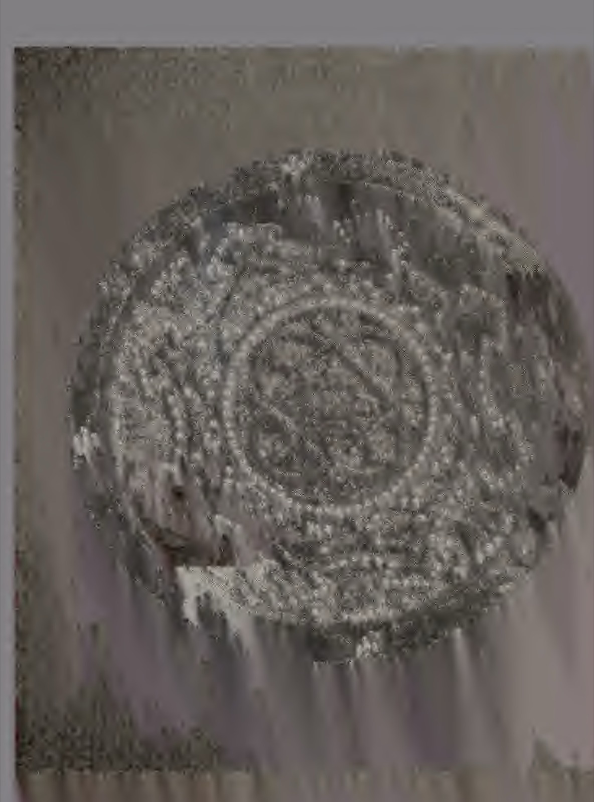 A round plate inlaid with beads in a dense radiating pattern, photographed against a plain cloth.
