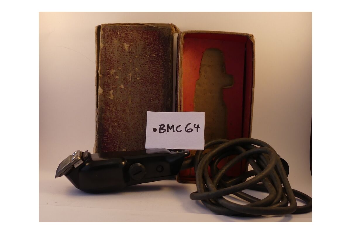 Electric hair clippers and cable beside their worn case, labelled BMC64.