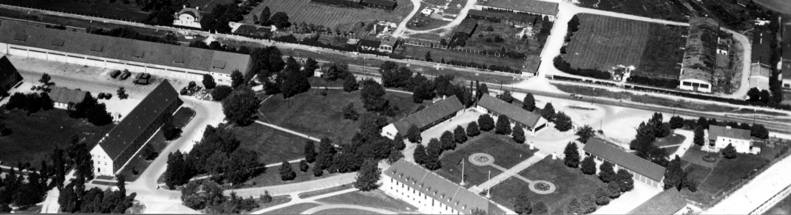 An aerial photograph of the Funkkaserne compound in northern Munich, showing rows of long barrack blocks beside a straight road.