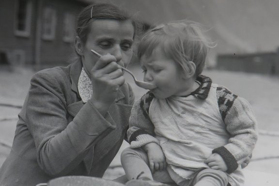 A mother feeding her daughter at the Landeck camp, 5 June 1945.