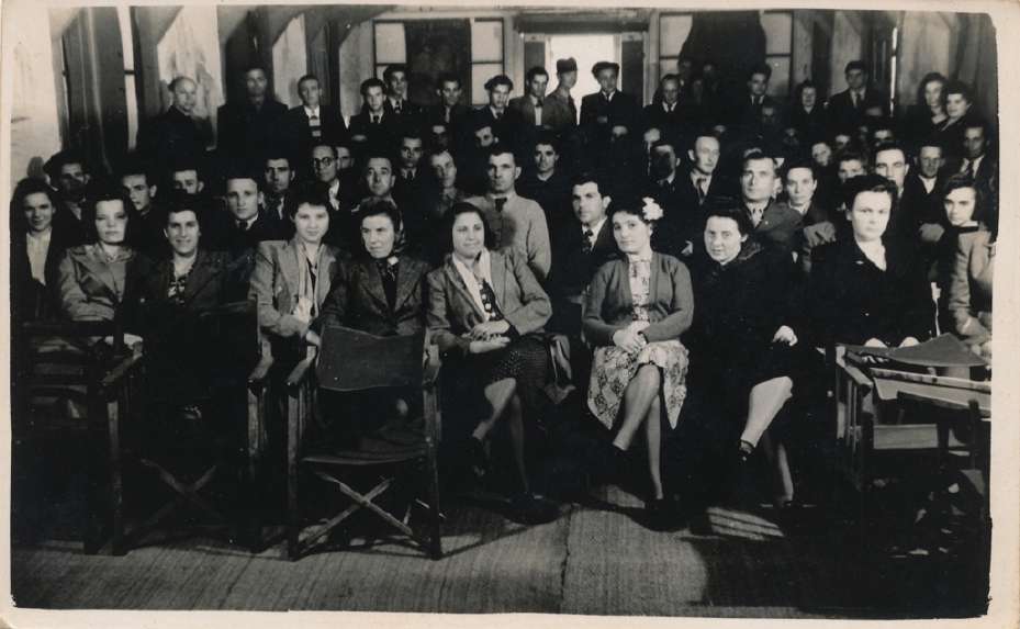 Men and women gathered in rows inside a room for a lecture.