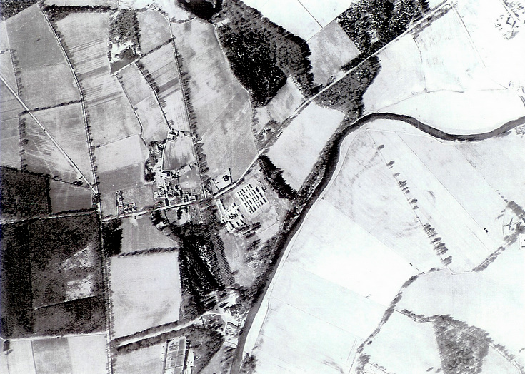 Aerial view of the camp beside fields and a curving river.