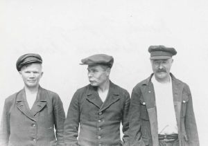 Three men wearing jackets and caps