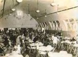 Tables and seated diners inside a large arched-roof dining hall.