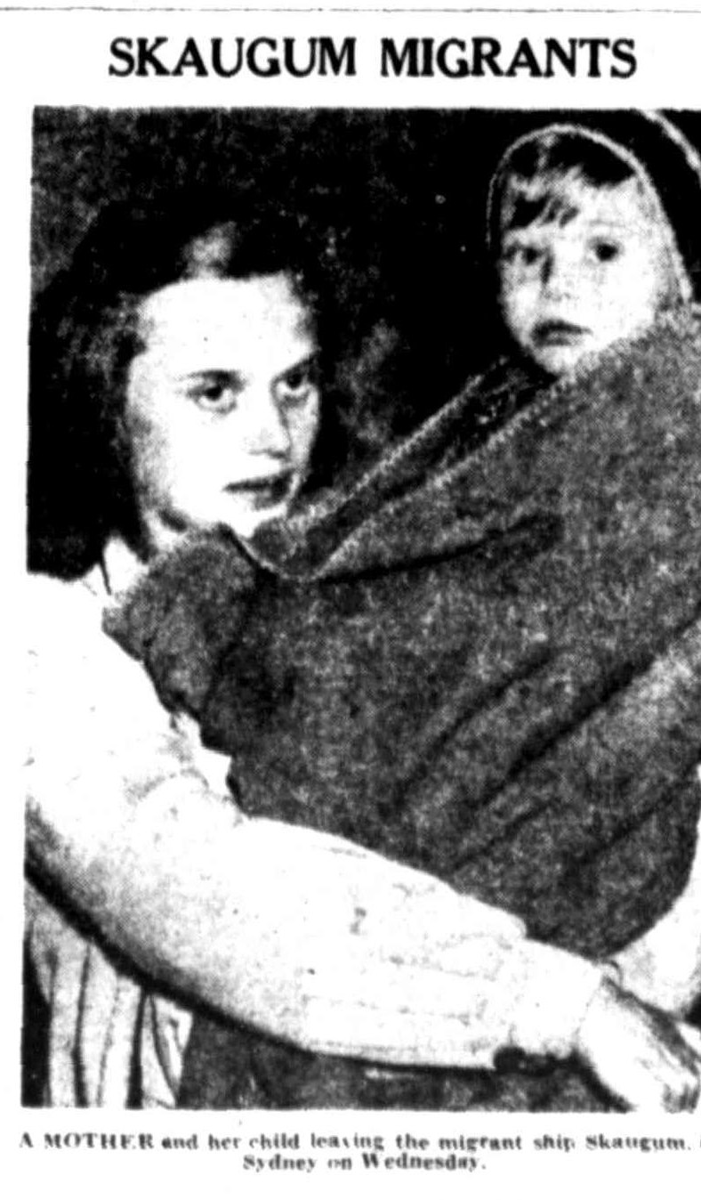 Newspaper photograph headed ‘Skaugum migrants’ showing a young woman carrying a small child wrapped in a blanket.