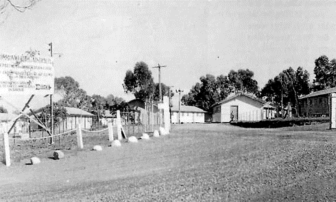 A road through Somers Camp with low wooden buildings and an entrance sign