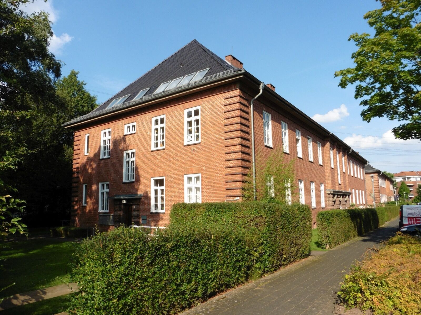 A long brick barrack block of the former Bismarck-Kaserne at Wentorf, with rows of windows and mature trees in front.